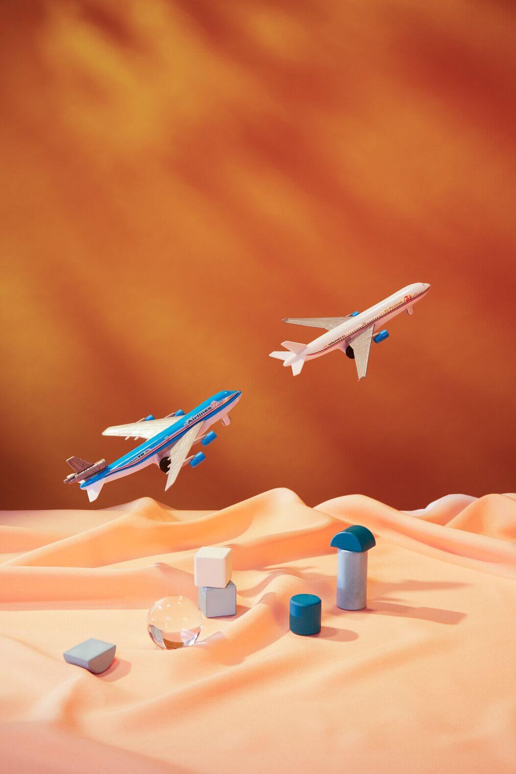 Two airplanes taking off with building blocks below representing buildings on the ground